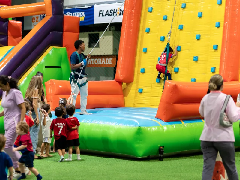 Niños esperan su turno frente a una pared inflable de escalar