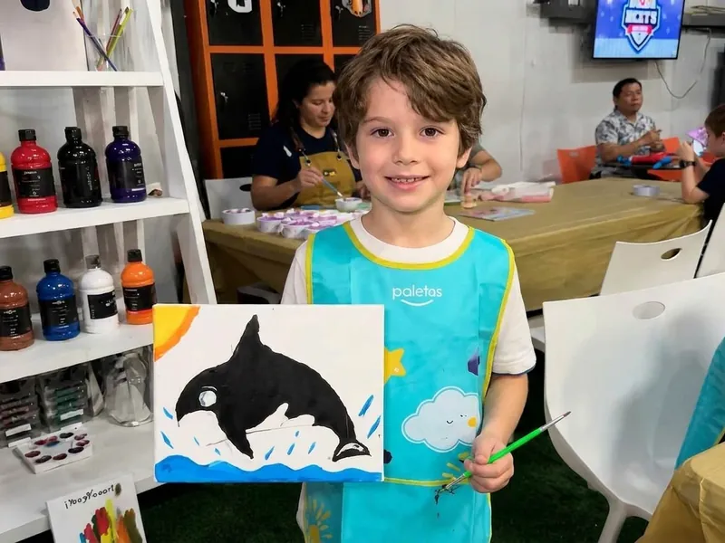 Niño muestra orgulloso su creación durante una actividad de fiesta