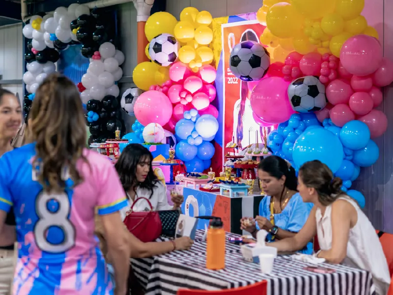 Mamás conversando en la mesa durante un cumpleaños, con el arco de globos de fondo